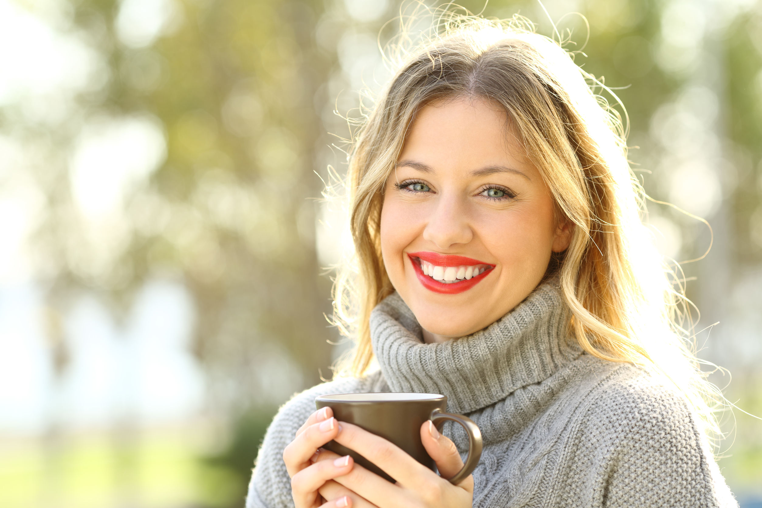 Happy woman looking at camera with a cup of coffee